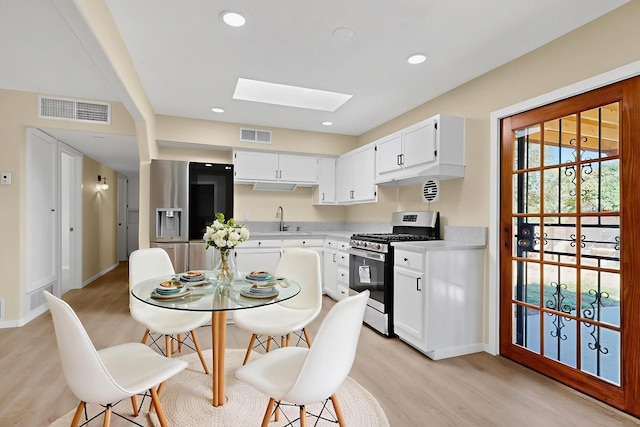 10409 Britt Ct NE, Albuquerque, NM 87112 - kitchen featuring appliances with stainless steel finishes, a skylight, light wood-type flooring, light countertops, and recessed lighting