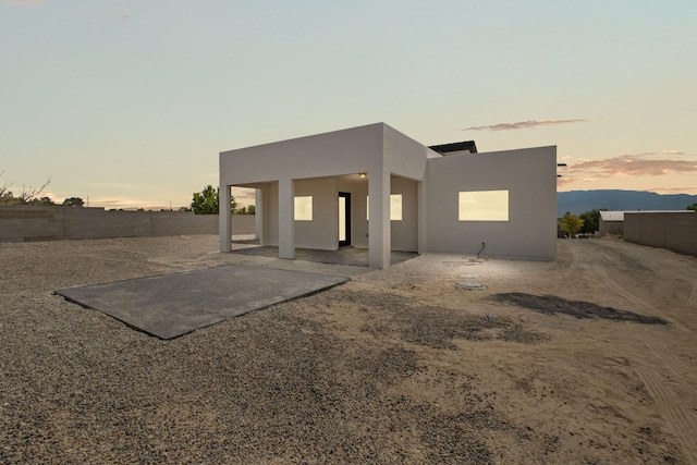 1109 11th St SE, Rio Rancho, NM 87124 - back of property at dusk with a patio area, stucco siding, and a fenced backyard