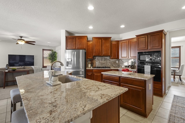 44 Los Balcones Pl NE, Rio Rancho, NM 87124 - kitchen featuring black appliances, an island with sink, light tile patterned flooring, ceiling fan, and a textured ceiling