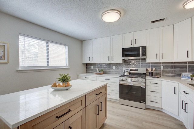 4920 Black Dr NW, Albuquerque, NM 87120 - kitchen featuring stainless steel appliances, backsplash, light wood-style floors, a textured ceiling, and white cabinets