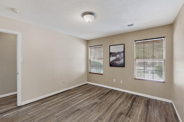 10639 Miera Dr NW, Albuquerque, NM 87114 - spare room featuring wood finished floors, plenty of natural light, a textured ceiling, and a smoke detector