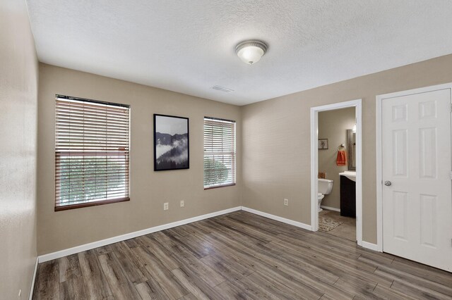 10639 Miera Dr NW, Albuquerque, NM 87114 - unfurnished bedroom featuring wood finished floors, ensuite bathroom, and a textured ceiling