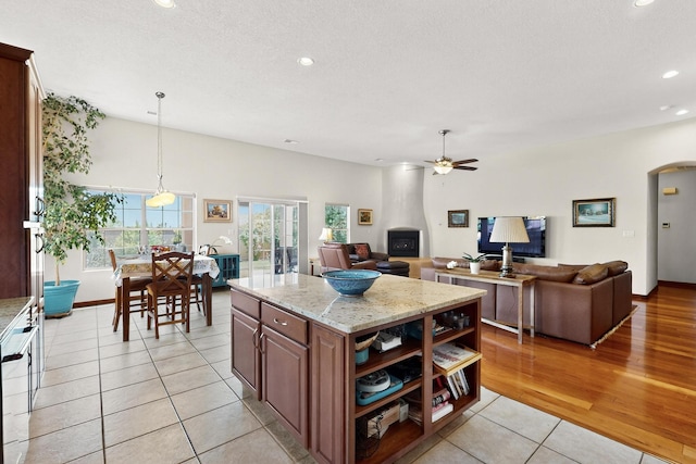 8712 Sandwater Rd NW, Albuquerque, NM 87120 - kitchen featuring ceiling fan, light tile patterned floors, arched walkways, light stone counters, and recessed lighting