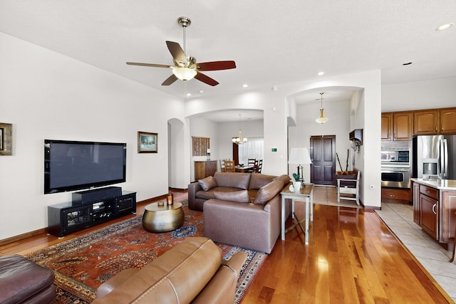 8712 Sandwater Rd NW, Albuquerque, NM 87120 - living room with arched walkways, light wood-style floors, a ceiling fan, a chandelier, and recessed lighting