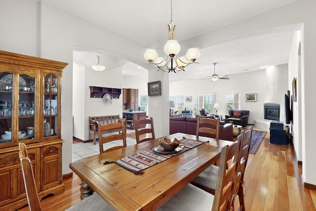8712 Sandwater Rd NW, Albuquerque, NM 87120 - dining room featuring arched walkways, a ceiling fan, a chandelier, and light wood finished floors