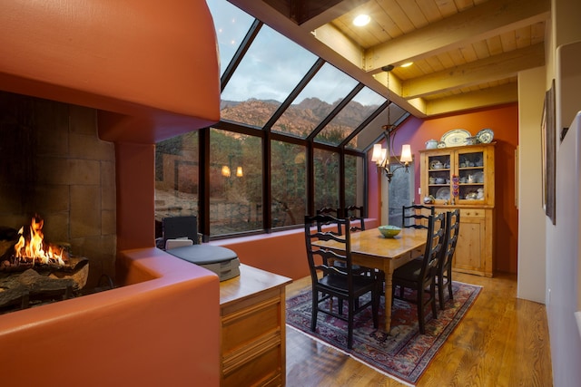 213 Spring Creek Pl NE, Albuquerque, NM 87122 - dining space with a chandelier, wood finished floors, a mountain view, a wood ceiling with exposed beams, and a warm lit fireplace