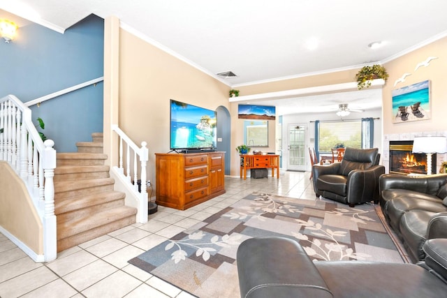 6412 Saint Josephs Ave NW, Albuquerque, NM 87120 - living room with ornamental molding, light tile patterned floors, ceiling fan, arched walkways, and a warm lit fireplace