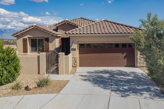 6417 Kings Cyn NE, Rio Rancho, NM 87144 - view of front of house with an attached garage, concrete driveway, a gate, stucco siding, and stone siding
