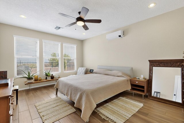 6417 Kings Cyn NE, Rio Rancho, NM 87144 - bedroom with a wall mounted air conditioner, light wood finished floors, a textured ceiling, recessed lighting, and ceiling fan