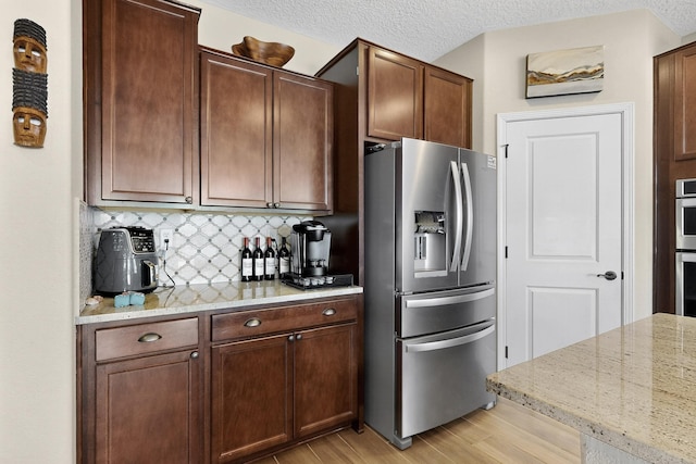 6417 Kings Cyn NE, Rio Rancho, NM 87144 - kitchen featuring stainless steel appliances, light wood-type flooring, tasteful backsplash, light stone counters, and a textured ceiling