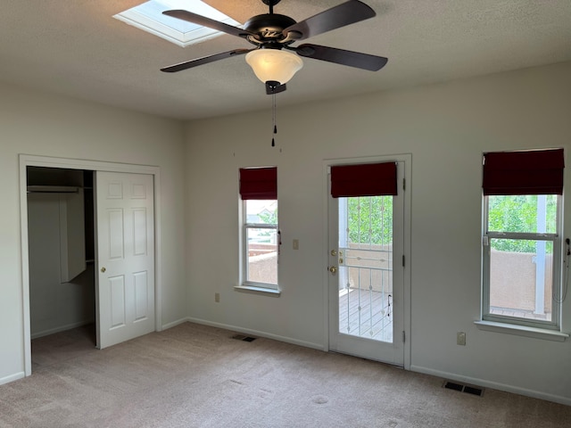5400 Pegasus Dr NW, Albuquerque, NM 87120 - unfurnished bedroom featuring light carpet, a skylight, a closet, access to outside, and a textured ceiling