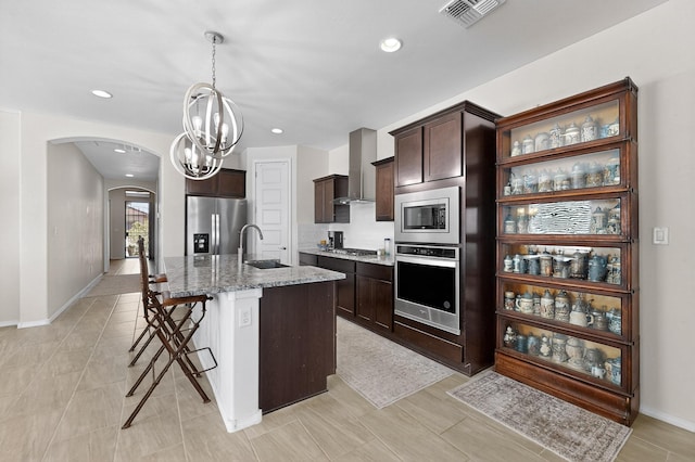 4293 Crowned Eagle Loop NE, Rio Rancho, NM 87144 - kitchen with appliances with stainless steel finishes, arched walkways, wall chimney exhaust hood, dark brown cabinets, and recessed lighting