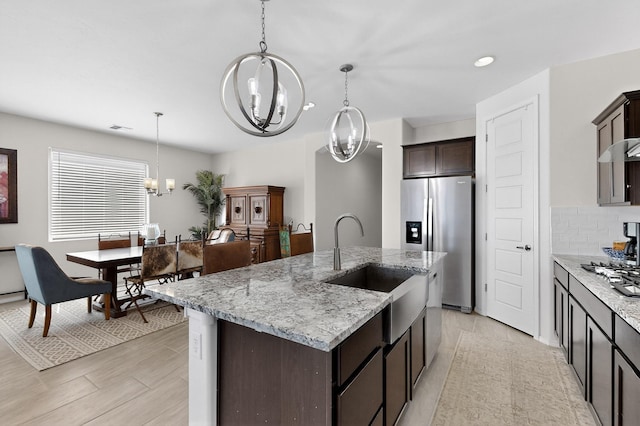 4293 Crowned Eagle Loop NE, Rio Rancho, NM 87144 - kitchen with a chandelier, stainless steel refrigerator with ice dispenser, dark brown cabinetry, pendant lighting, and light stone countertops