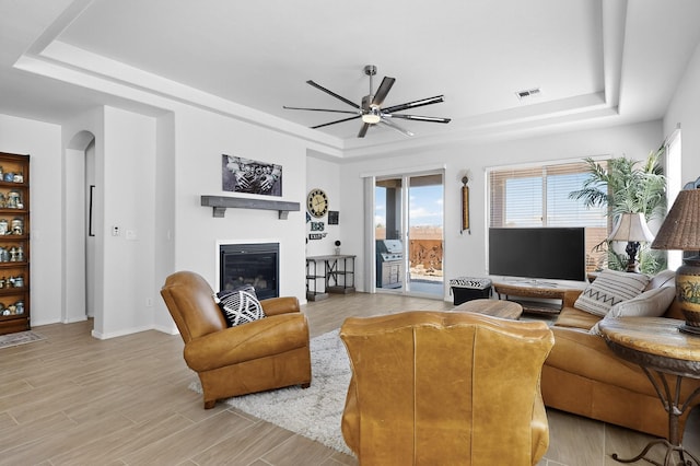 4293 Crowned Eagle Loop NE, Rio Rancho, NM 87144 - living area featuring a raised ceiling, ceiling fan, a glass covered fireplace, and light wood-style floors