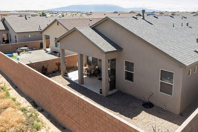 4293 Crowned Eagle Loop NE, Rio Rancho, NM 87144 - rear view of property featuring roof with shingles, stucco siding, a patio area, and a fenced backyard