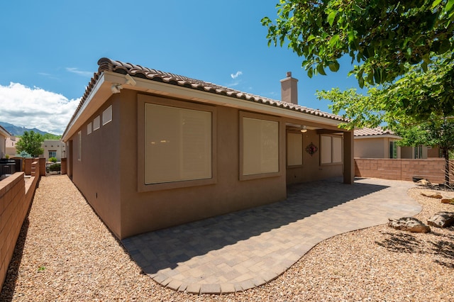 959 Salt Cedar Ct, Bernalillo, NM 87004 - rear view of house with stucco siding, a chimney, a patio, and a tiled roof