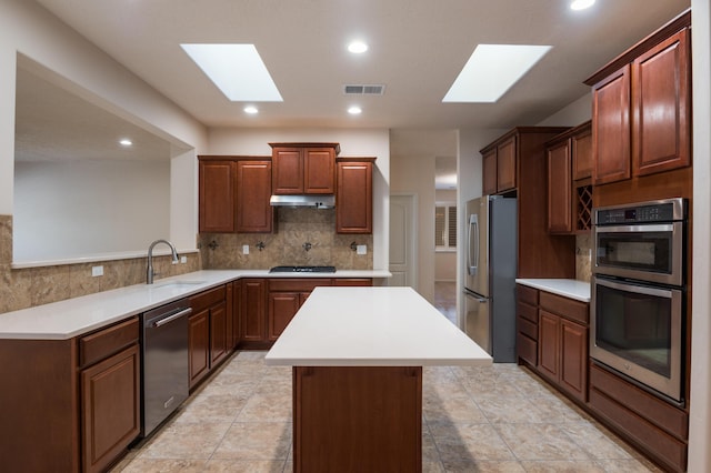 959 Salt Cedar Ct, Bernalillo, NM 87004 - kitchen with a skylight, stainless steel appliances, a kitchen island, tasteful backsplash, and light countertops