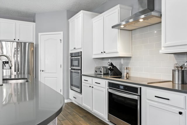 9015 Vista Dibujo Rd, Albuquerque, NM 87120 - kitchen with wall chimney range hood, appliances with stainless steel finishes, dark wood-type flooring, tasteful backsplash, and white cabinets