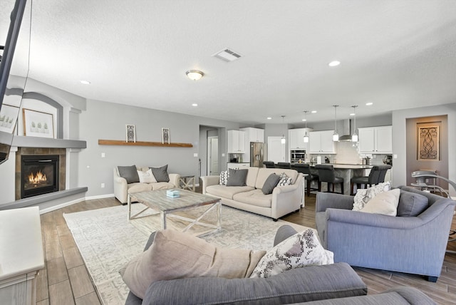 9015 Vista Dibujo Rd, Albuquerque, NM 87120 - living room featuring a glass covered fireplace, wood finished floors, a textured ceiling, and recessed lighting