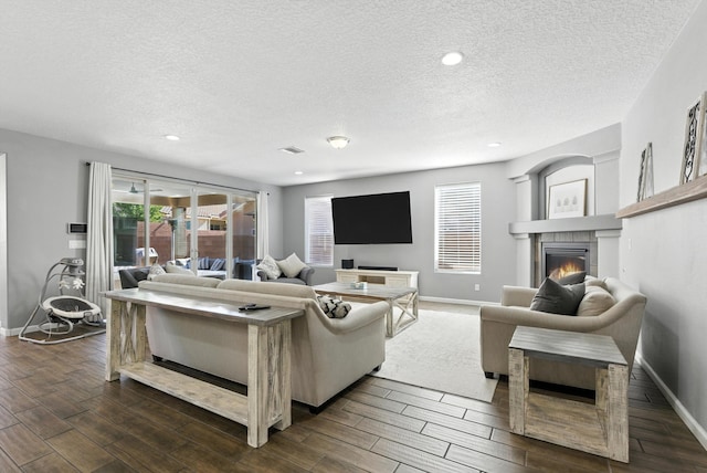 9015 Vista Dibujo Rd, Albuquerque, NM 87120 - living room with a textured ceiling, dark wood-style flooring, a glass covered fireplace, and recessed lighting