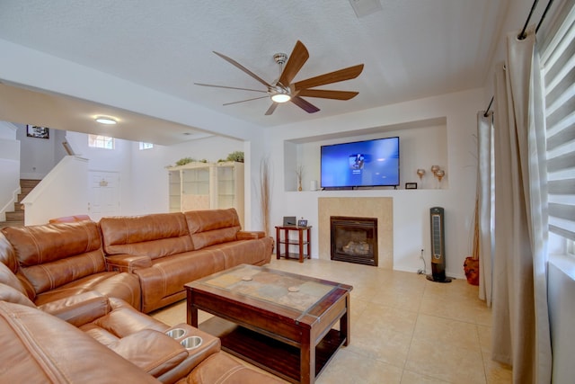 7024 Tree Line Ave NW, Albuquerque, NM 87114 - living room with a ceiling fan, stairs, a tiled fireplace, and light tile patterned floors