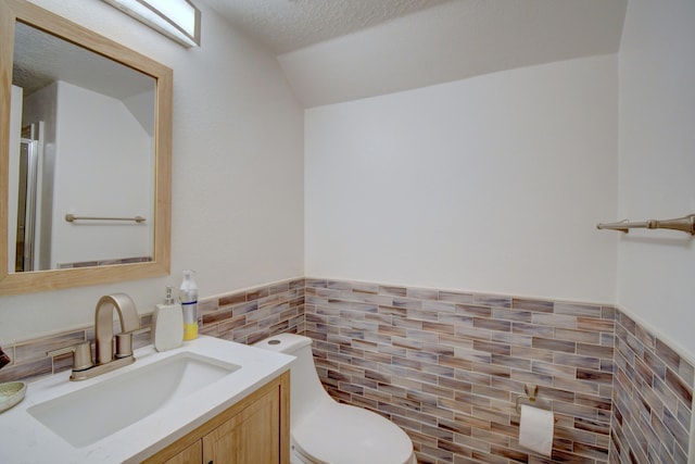 7024 Tree Line Ave NW, Albuquerque, NM 87114 - bathroom with tile walls, vanity, lofted ceiling, wainscoting, and a shower with door