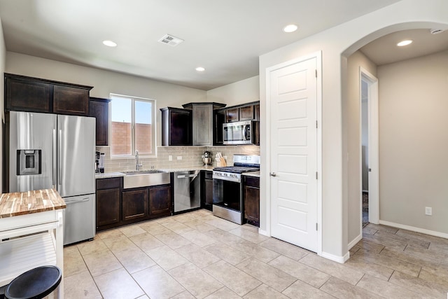 4236 Crowned Eagle Loop NE, Rio Rancho, NM 87144 - kitchen featuring stainless steel appliances, arched walkways, backsplash, dark brown cabinetry, and light stone countertops