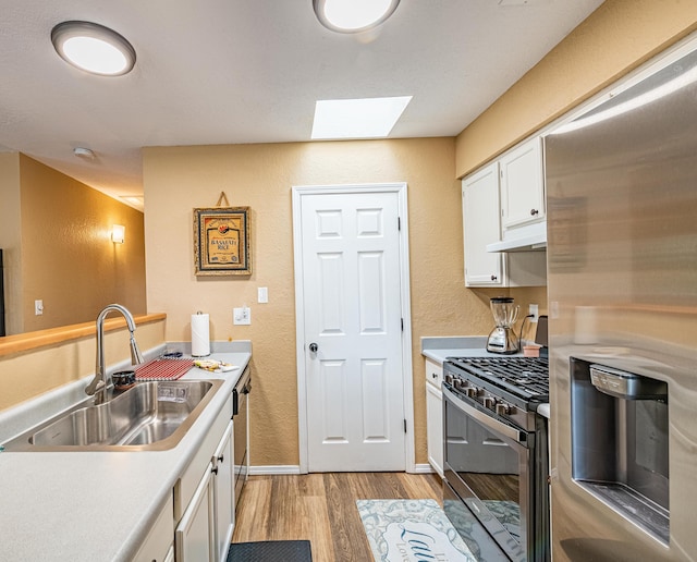 2900 Vista Del Rey NE Unit 18D, Albuquerque, NM 87112 - kitchen with appliances with stainless steel finishes, light wood-style floors, a skylight, white cabinetry, and light countertops