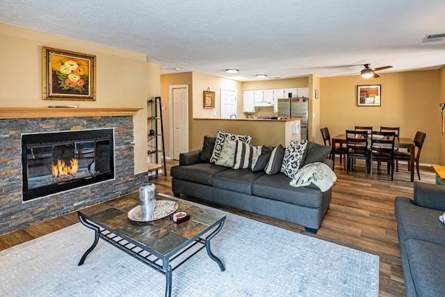 2900 Vista Del Rey NE Unit 18D, Albuquerque, NM 87112 - living area with wood finished floors, ceiling fan, a stone fireplace, and a textured ceiling