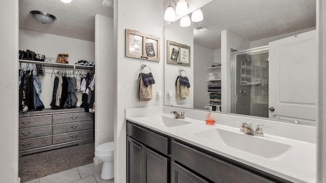 2404 Del Timbre Ln SW, Albuquerque, NM 87121 - full bathroom featuring a textured ceiling, double vanity, a shower stall, a walk in closet, and tile patterned flooring