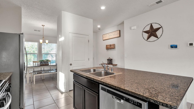 2404 Del Timbre Ln SW, Albuquerque, NM 87121 - kitchen with stainless steel appliances, dark countertops, an island with sink, light tile patterned flooring, and a chandelier