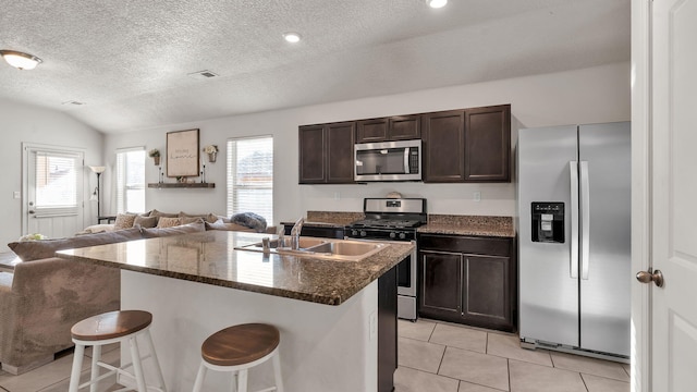 2404 Del Timbre Ln SW, Albuquerque, NM 87121 - kitchen with stainless steel appliances, open floor plan, light tile patterned floors, dark brown cabinetry, and a textured ceiling
