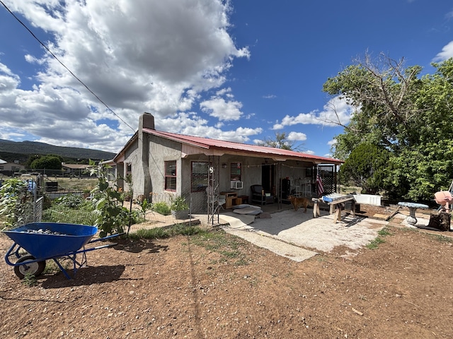 2 Bus Ln, Sandia Park, NM 87047 - back of house featuring a chimney, a patio, stucco siding, and a metal roof