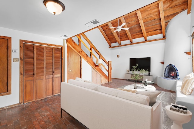 118 Sandia View Rd, Corrales, NM 87048 - living room with a warm lit fireplace, stairway, a ceiling fan, brick flooring, and lofted ceiling