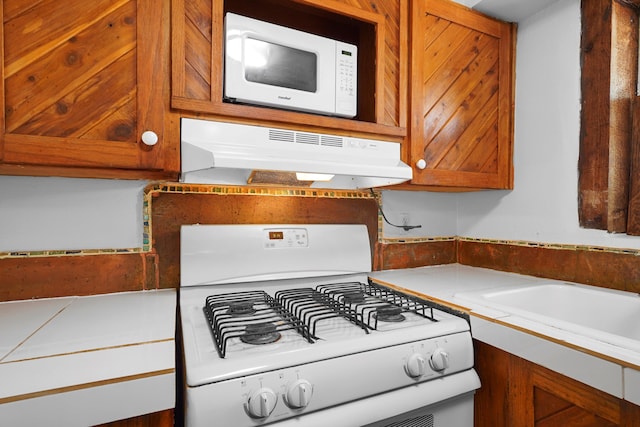 118 Sandia View Rd, Corrales, NM 87048 - kitchen with white appliances, under cabinet range hood, brown cabinetry, and light countertops