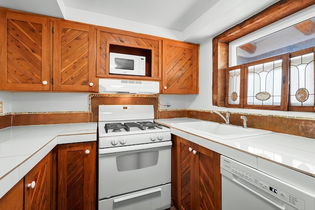 118 Sandia View Rd, Corrales, NM 87048 - kitchen with white appliances, under cabinet range hood, brown cabinetry, and tile countertops