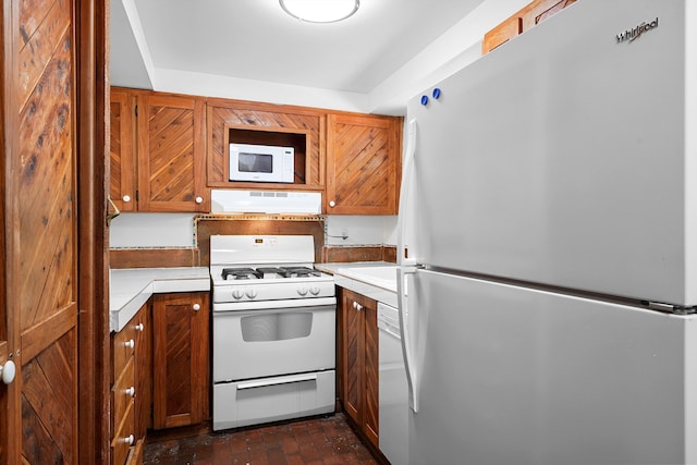 118 Sandia View Rd, Corrales, NM 87048 - kitchen featuring white appliances, under cabinet range hood, light countertops, brick flooring, and brown cabinets