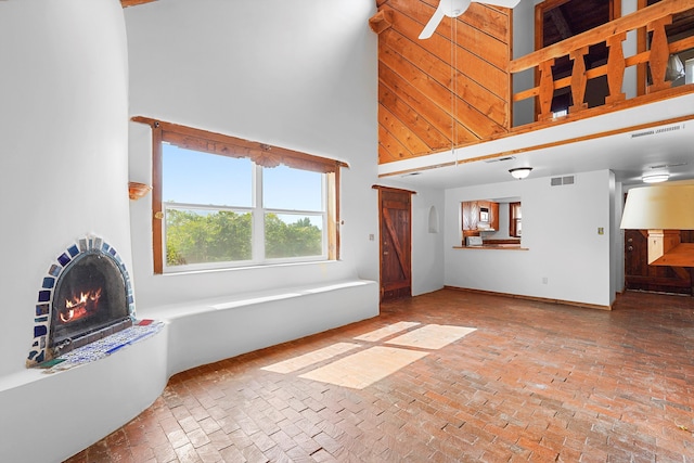118 Sandia View Rd, Corrales, NM 87048 - unfurnished living room featuring brick floors, a high ceiling, and a warm lit fireplace