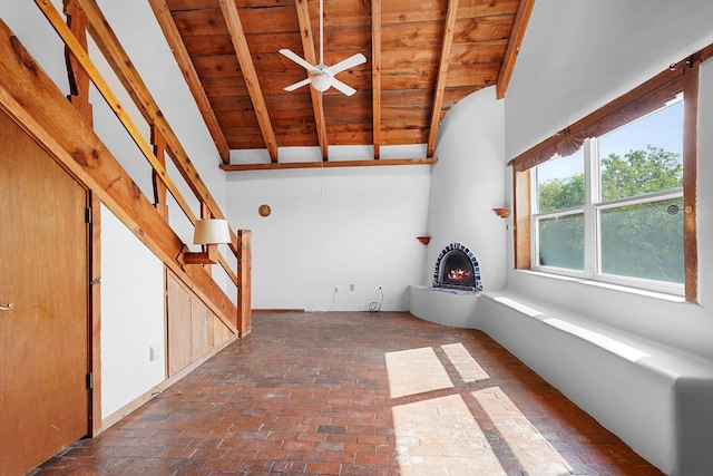 118 Sandia View Rd, Corrales, NM 87048 - unfurnished living room with a wood ceiling with exposed beams, a ceiling fan, brick flooring, and a warm lit fireplace