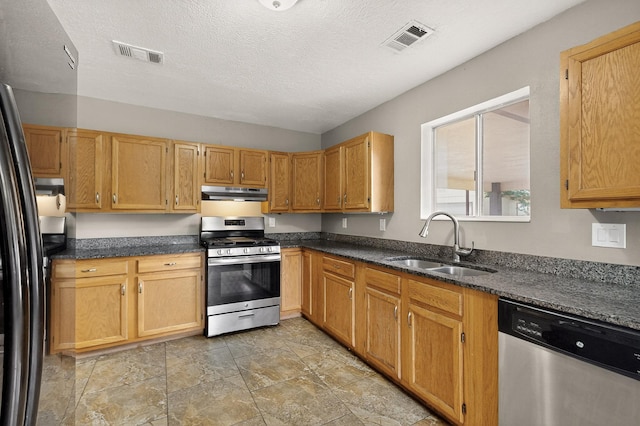 1519 Lundy Ln SW, Albuquerque, NM 87105 - kitchen with appliances with stainless steel finishes, under cabinet range hood, dark stone countertops, a textured ceiling, and light stone finish floors