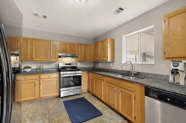 1519 Lundy Ln SW, Albuquerque, NM 87105 - kitchen with appliances with stainless steel finishes, under cabinet range hood, a textured ceiling, and dark stone counters