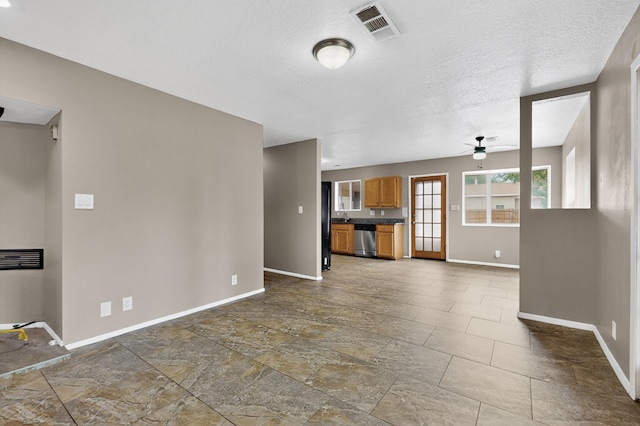 1519 Lundy Ln SW, Albuquerque, NM 87105 - unfurnished living room with a ceiling fan, a textured ceiling, and dark stone finish flooring