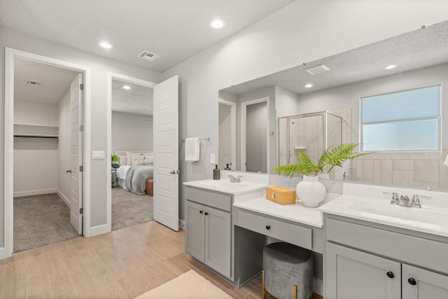 2520 Guadalupe Rd NE, Rio Rancho, NM 87144 - bathroom with double vanity, wood finished floors, a stall shower, connected bathroom, and a textured ceiling