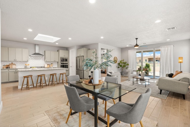 2520 Guadalupe Rd NE, Rio Rancho, NM 87144 - dining space with a textured ceiling, light wood-style floors, recessed lighting, a skylight, and ceiling fan
