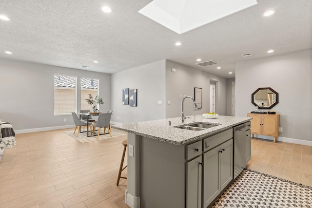 2520 Guadalupe Rd NE, Rio Rancho, NM 87144 - kitchen featuring gray cabinets, dishwasher, an island with sink, light wood finished floors, and a textured ceiling