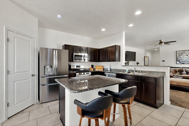 2332 Del Timbre Ln SW, Albuquerque, NM 87121 - kitchen with stainless steel appliances, a peninsula, a textured ceiling, dark brown cabinetry, and light tile patterned flooring