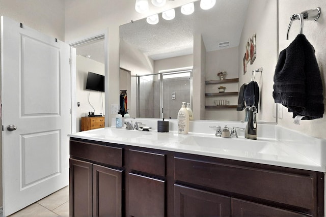 2332 Del Timbre Ln SW, Albuquerque, NM 87121 - bathroom featuring a stall shower, double vanity, tile patterned floors, and a textured ceiling