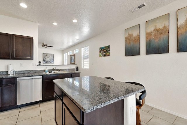 2332 Del Timbre Ln SW, Albuquerque, NM 87121 - kitchen featuring stainless steel dishwasher, light tile patterned flooring, ceiling fan, dark brown cabinetry, and a center island