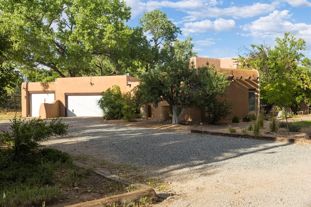 2505 Elfego Rd NW, Albuquerque, NM 87107 - pueblo-style home featuring dirt driveway, stucco siding, and an attached garage
