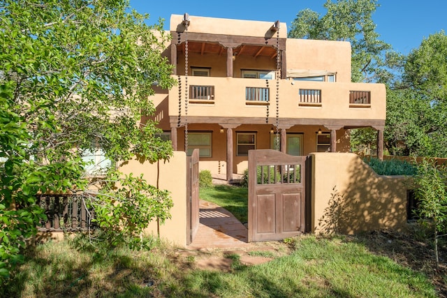 2505 Elfego Rd NW, Albuquerque, NM 87107 - view of front of property featuring a balcony, stucco siding, a gate, and a fenced front yard